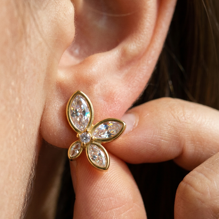 Close-up of marquise zircon flower stud earring on ear, gold bezel-set CZ petals detail shot
