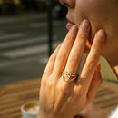 Woman wearing gold marquise crystal double band ring at outdoor café, ring on index finger, warm afternoon light
