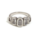 Silver oval and cushion multi-stone ring on white background, bezel-set oval center stone flanked by four cushion-cut accent stones, fine band shown in three-quarter angle, cool light with long shadow
