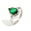 Silver green teardrop stone halo cocktail ring on white background, mint green faceted teardrop stone in multi-prong silver halo setting, tapered silver band, soft shadow
