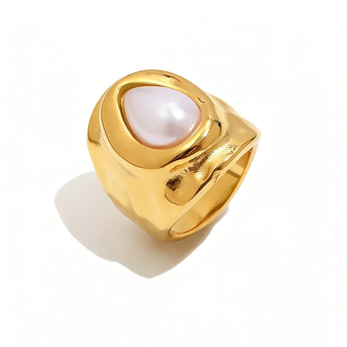Gold hammered pearl chunky ring on white background, wide organic-surface band with bezel-set teardrop pearl at center, sculptural molten gold texture visible on band sides, long warm shadow
