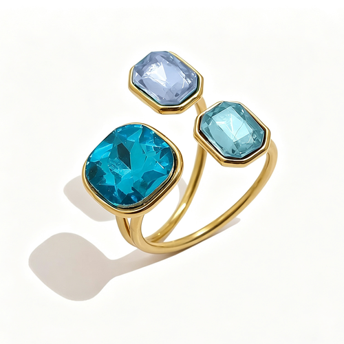 Gold triple stone open cocktail ring in Lagoon colorway on white background, large teal cushion stone with aqua blue and pale blue octagon stones in graduated bezel settings, open band with warm shadow
