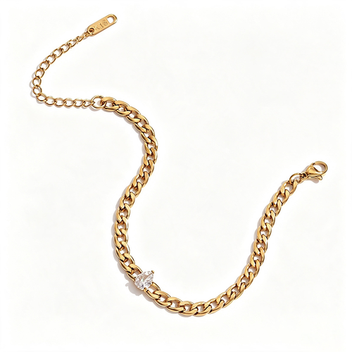 Gold Cuban link bracelet with pear-cut stone laid flat on white background in S-curve, pear-shaped stone prong-set into curb links, lobster clasp on right and extender chain with tag on left, warm light
