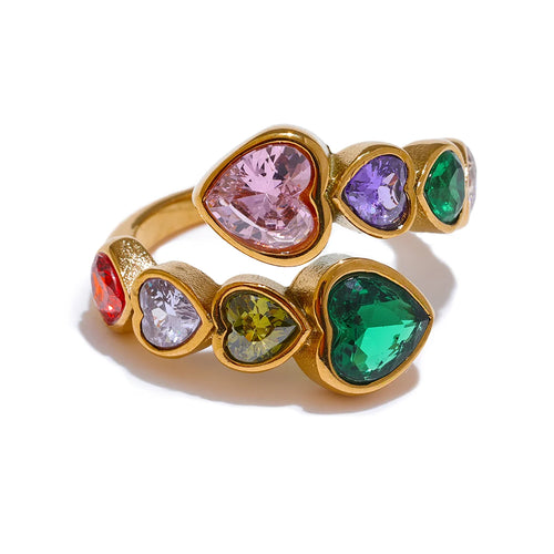 Gold multicolor heart stone open ring on white background, colorful heart-cut stones in alternating double-row arrangement showing pink, purple, green, red and olive stones in gold bezel settings, open adjustable band
