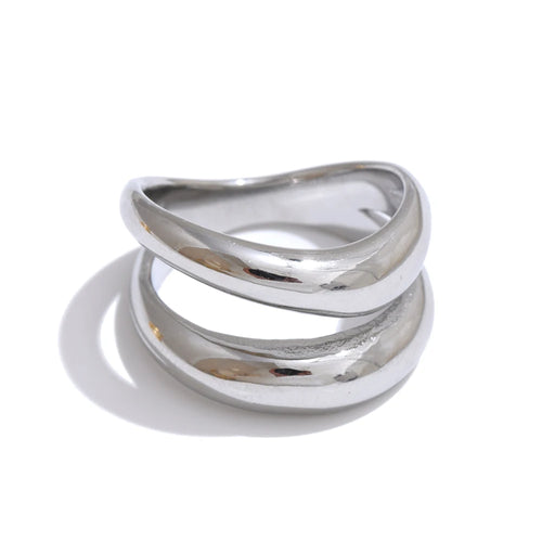 Silver double wave band ring on white background, two-band wave structure with upper band arching above lower band, mirror-polished silver surface, cool light with long directional shadow
