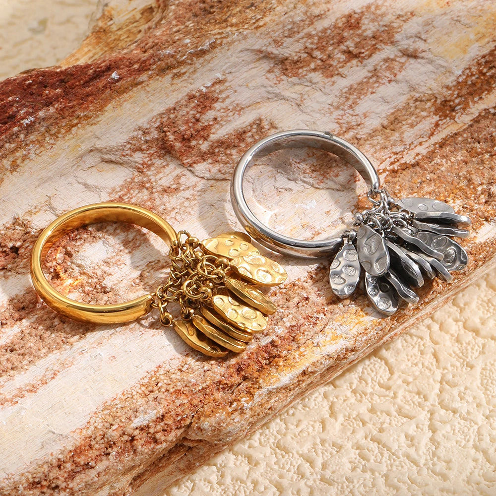 Hammered teardrop fringe rings in gold and silver on marble surface, statement ring detail
