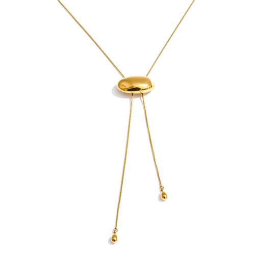 Gold oval slider lariat necklace on white background, full length view showing fine snake chain threaded through polished dome oval, two uneven chain ends with teardrop tips, clean white background with soft shadow
