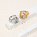 Gold and silver oversized emerald cut chunky rings resting on white plaster step against cream background, side angle showing organic band profile, chunky band thickness and irregular shoulder outline visible
