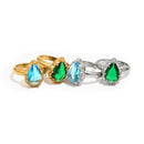 Four teardrop stone halo cocktail rings on white background showing all colorways, gold band with blue and green teardrop stones and silver band with blue and green teardrop stones, multi-prong halo setting visible
