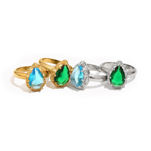 Four teardrop stone halo cocktail rings on white background showing all colorways, gold band with blue and green teardrop stones and silver band with blue and green teardrop stones, multi-prong halo setting visible
