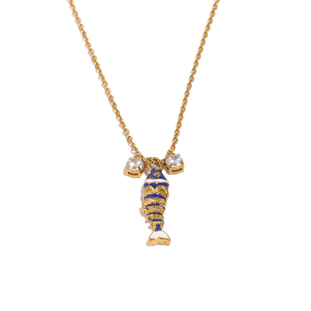 Navy blue enamel fish pendant necklace on gold cable chain, crystal accent detail, white background
