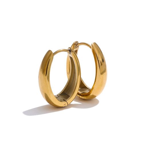 Pair of gold chunky hoop earrings on white background, thick polished tube hoops in three-quarter angle showing inner curve and hinged clasp detail, warm light with long shadow
