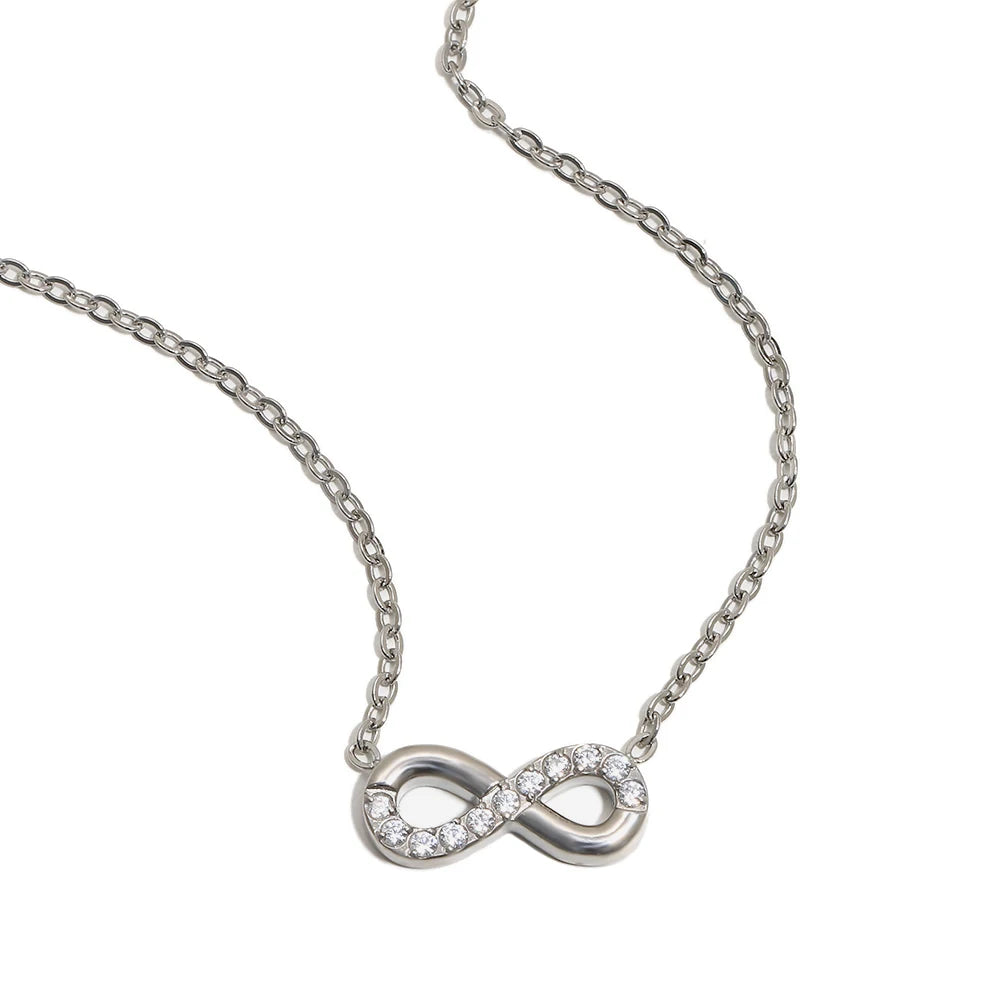Infinity pendant necklace in silver, pavé crystal infinity symbol on cable chain, white background
