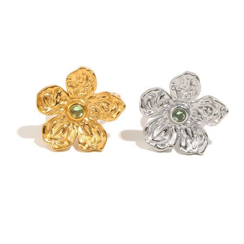 Gold and silver hammered texture flower rings side by side, five-petal sculptural bloom with green stone center, white background
