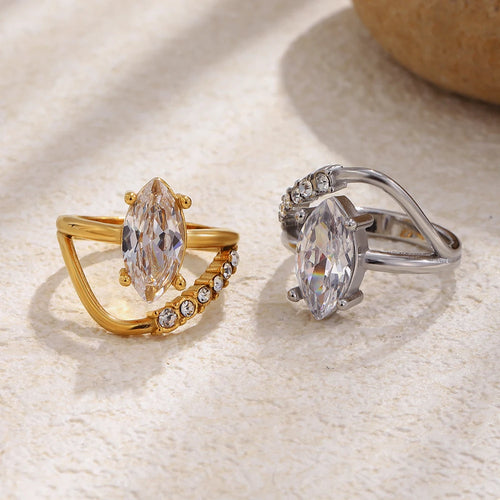 Marquise crystal double band ring in gold and silver side by side, split band detail visible, natural stone background
