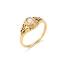 Gold filigree freshwater pearl ring on white background, three-quarter side angle showing scrollwork filigree depth, beaded bezel height and fine band tapering toward shank, warm directional light
