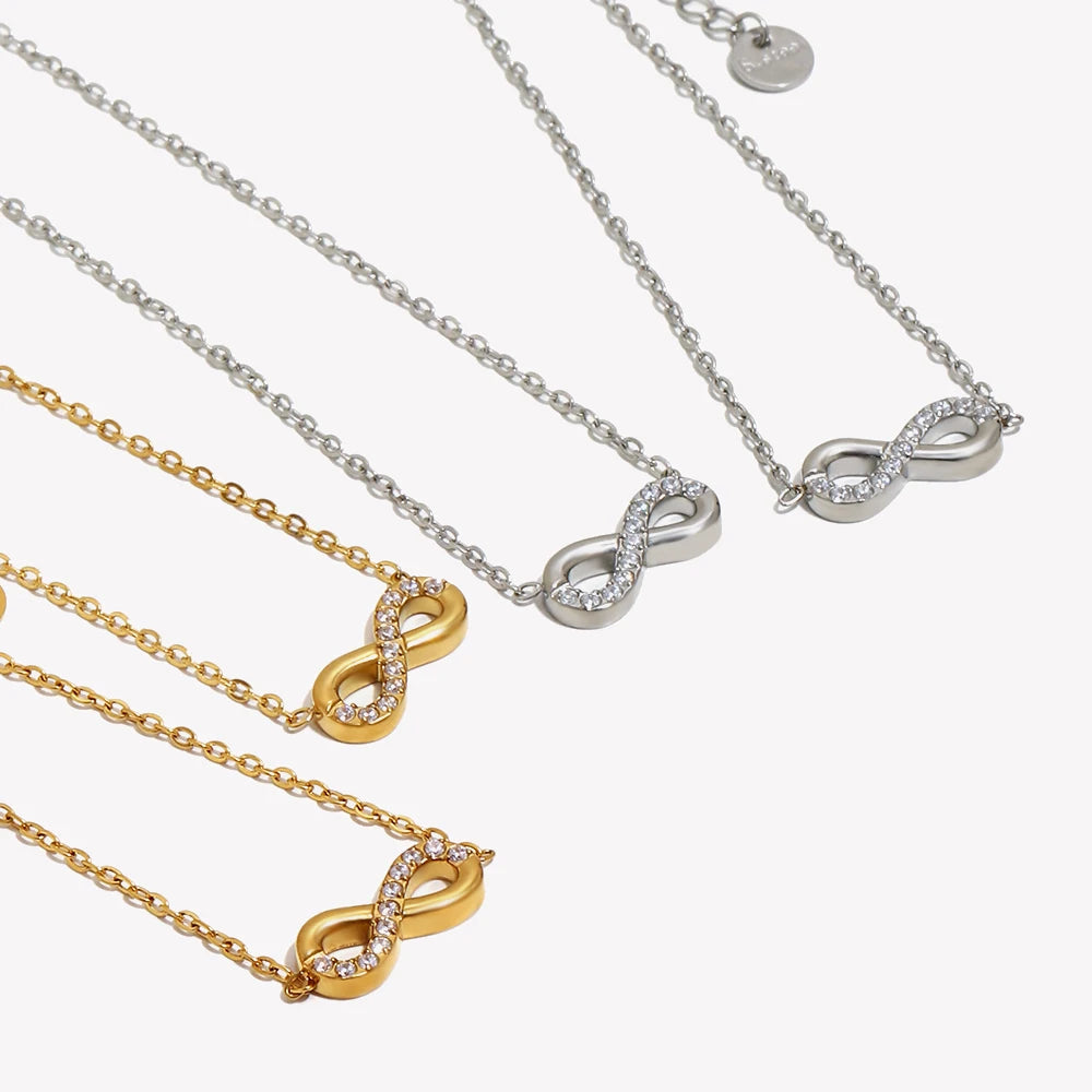 Infinity pendant necklaces in gold and silver, both colorways flat lay, pavé crystal infinity symbol

