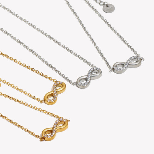 Infinity pendant necklaces in gold and silver, both colorways flat lay, pavé crystal infinity symbol
