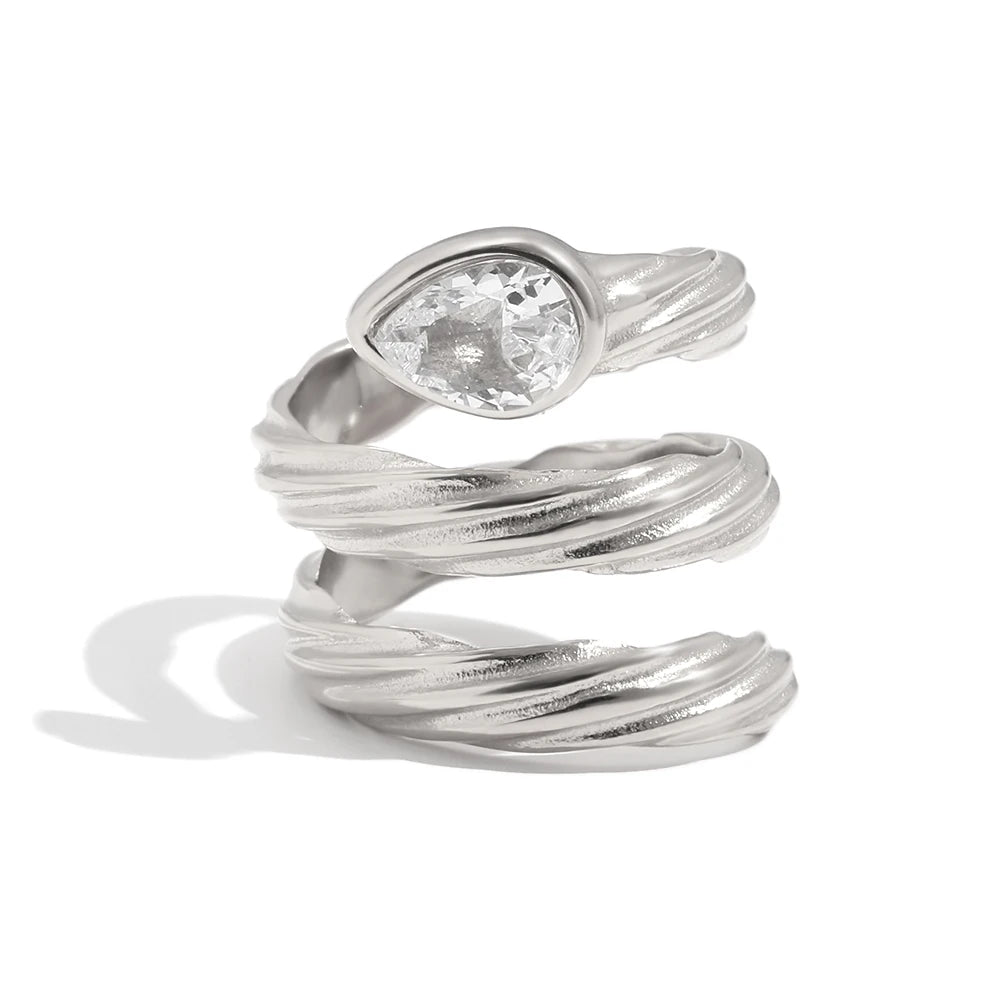 Spiral wrap ring in silver close-up, pear-cut crystal in smooth bezel at crown, rope-textured coiling band, white background
