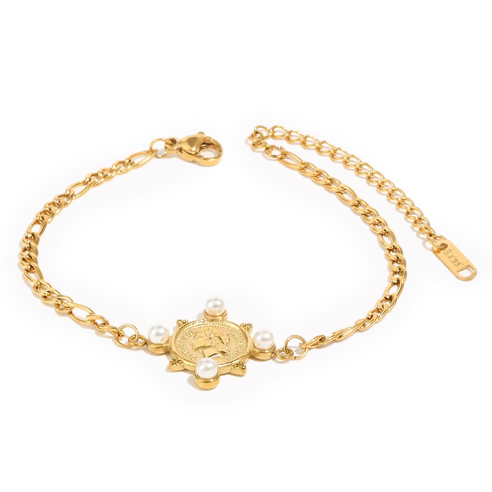 Gold pearl coin charm Figaro chain bracelet on white background, engraved round coin with four pearl accents at corners, alternating Figaro chain links, lobster clasp and extender chain visible
