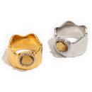 Wavy wide band crystal circle ring in gold and silver, amber center stone with pavé halo, white background
