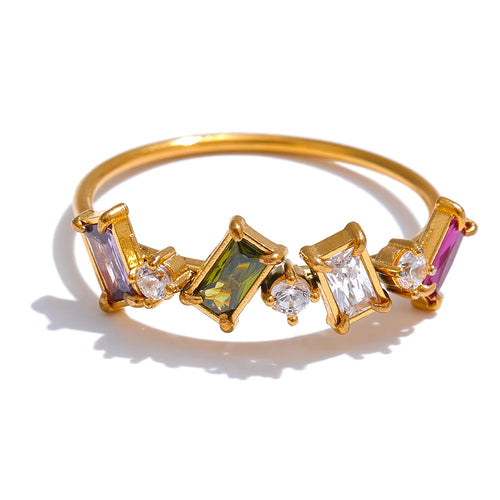 Gold geometric multi-stone ring on white background, close-up of multicolor colorway showing purple, olive green and clear baguette stones with round accent stones, prong settings on fine gold band, warm light
