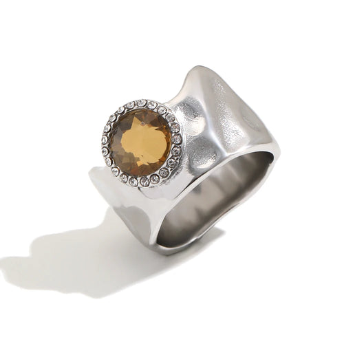 Wavy wide band crystal circle ring in silver, amber round stone with pavé surround on sculptural band, white background
