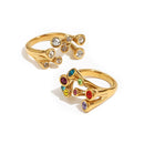 Gold multicolor stone scatter open band ring and clear stone version side by side on white background, nine bezel-set stones in scattered arrangement, open band visible

