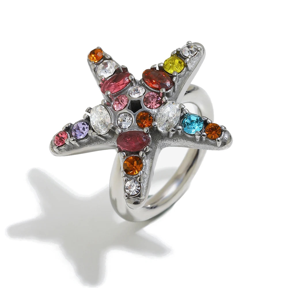 Colorful crystal starfish ring in silver, close-up of multicolor prong-set stones, white background
