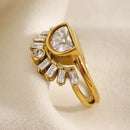 Gold half moon fan stacked ring on cream fabric surface, three-quarter side angle showing half-moon bezel depth, baguette fan stone arrangement and split double band gap, soft diffused light
