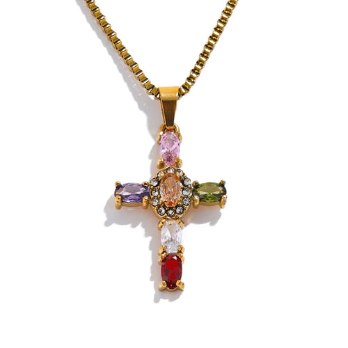 Gold multicolor stone cross pendant necklace on white background, cross pendant with pink, orange, purple, olive green, clear and red oval prong-set stones, pavé accent stones at center, gold box chain, warm light with long shadow

