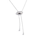 Silver oval slider lariat necklace on white background, polished dome oval slider on fine snake chain, two ends hanging at uneven lengths with teardrop tips, cool light with soft shadow beneath oval
