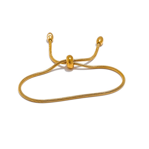 Gold snake chain slider bracelet on white background, oval loop shape showing barrel slider at center with two snake chain ends each tipped with a polished oval, soft shadow beneath
